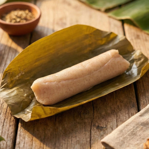 Mai-o-Mailee's Hmong Wheat Cake wrapped in a large green banana leaf on a wooden surface.