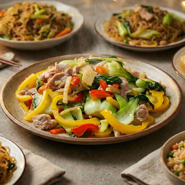 Plates of Mai-o-Mailee's Mom's All Purpose Seasoning stir-fried vegetables and meat with noodles on a wooden table.